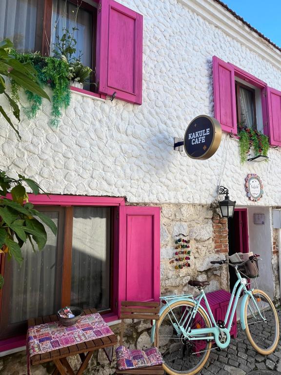 Tarihi taş duvarlar, pespembe panjurlar ve önünde huzurla bekleyen su yeşili bisikletimiz… Kakule Pansiyon’un sıcak ve samimi atmosferi tam da burada başlıyor! 🚲💕