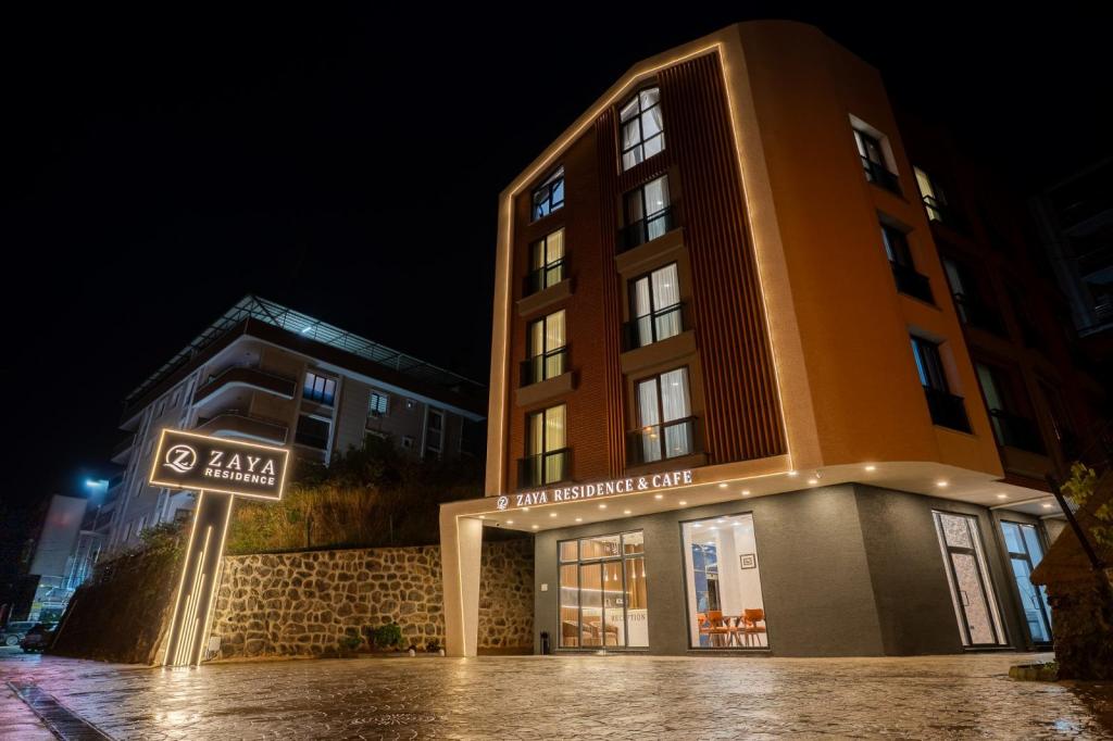Zaya Residence – Tesis AçıklamasıZaya Residence, Trabzon’un Yomra bölgesinde konforlu, modern ve keyifli bir konaklama deneyimi sunmaktadır. Farklı konaklama ihtiyaçlarına hitap eden 1+1 oda seçenekleri ile çiftler, aileler ve Trabzon’u keşfetmek isteyen misafirler için ideal bir konaklama alternatifidir.Tesisin odalarında konforlu yataklar, ayrı yaşam alanları, klima, ferah banyolar, minibar ve kettle gibi misafirlerin konaklama süresince ihtiyaç duyabileceği olanaklar bulunmaktadır. Bazı odalarda deniz manzarası ve Fransız balkonlu pencereler sunulurken, ekonomik oda seçenekleri manzara beklentisi olmayan misafirler için avantajlı bir alternatif oluşturmaktadır.Misafirlerin konforu düşünülerek odalarda ücretsiz su, çay ve kahve ikramı sunulmaktadır. Modern ve kullanışlı yaşam alanları sayesinde Zaya Residence, hem kısa süreli hem de daha uzun konaklamalar için rahat bir ortam sağlamayı amaçlamaktadır.Trabzon’un Yomra bölgesinde konumlanan Zaya Residence, şehri keşfetmek, iş seyahati gerçekleştirmek veya Karadeniz’in doğal güzelliklerinin tadını çıkarmak isteyen misafirler için konforlu bir konaklama deneyimi sunmaktadır.Zaya Residence – Konfor, ferahlık ve ev sıcaklığını bir arada keşfedin.